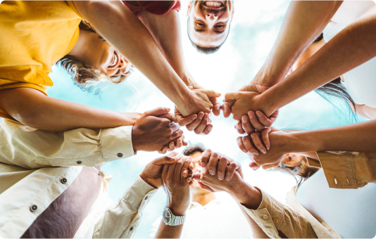 Imagem de um grupo de pessoas de mãos dadas formando um círculo com as mãos