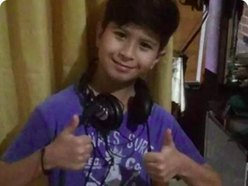 Menino sorridente com fones de ouvido no pescoço fazendo sinal de positivo com as duas mãos